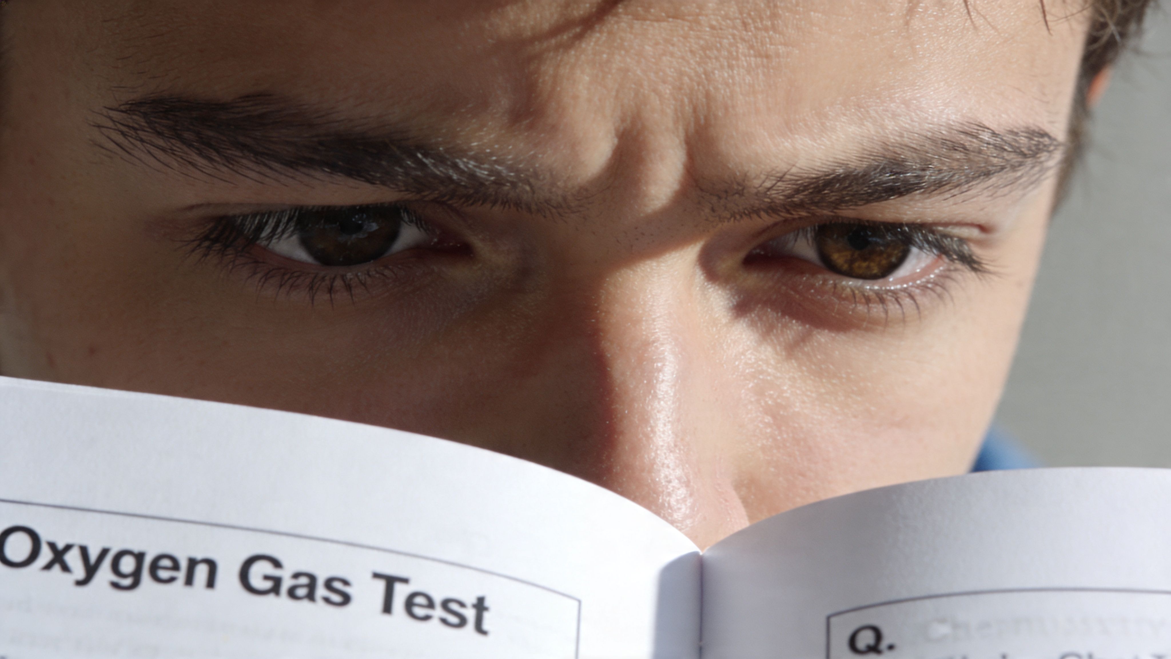 A young person intensely reading a chemistry textbook page titled Oxygen Gas Test with deep concentration.